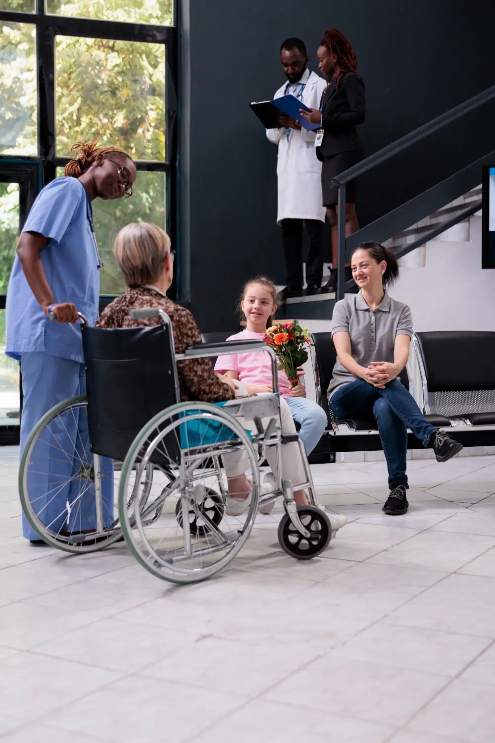 medical-assistant-bringing-old-patient-family-after-finishing-appointment-while-explaining-health-care-treatment-hospital-waiting-area-granddaughter-holding-bouquet-flowers-grandmother